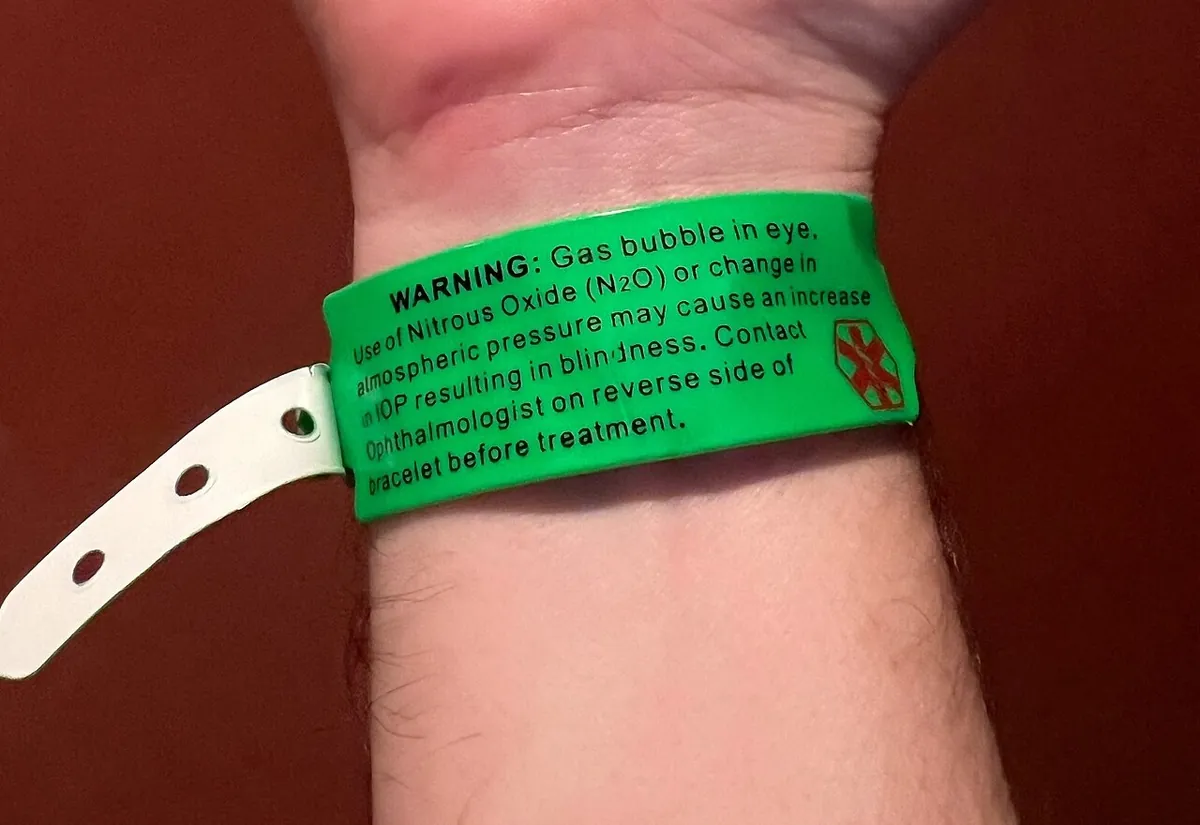 Pulso com pulseira verde de alerta informando que há gás dentro do olho após vitrectomia.