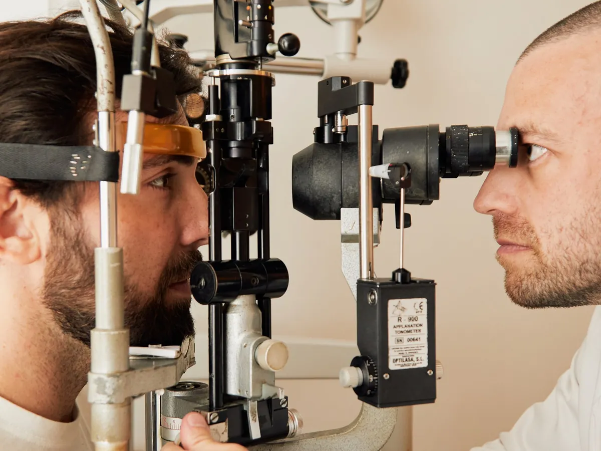 Médico observando o olho de uma pessoa em uma lâmpada de fenda, o microscópio usado para examinar a frente do olho.