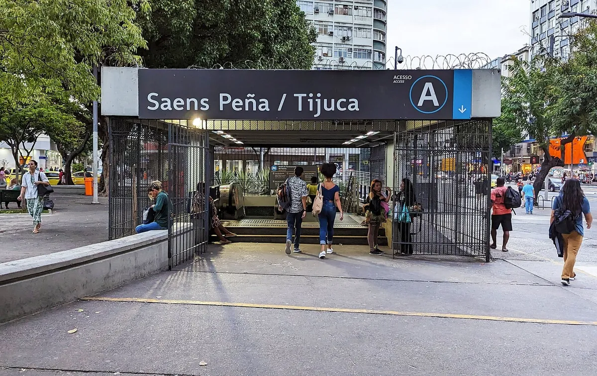 Entrada A da estação Saens Peña / Tijuca do metrô, com pessoas caminhando na calçada em frente.
