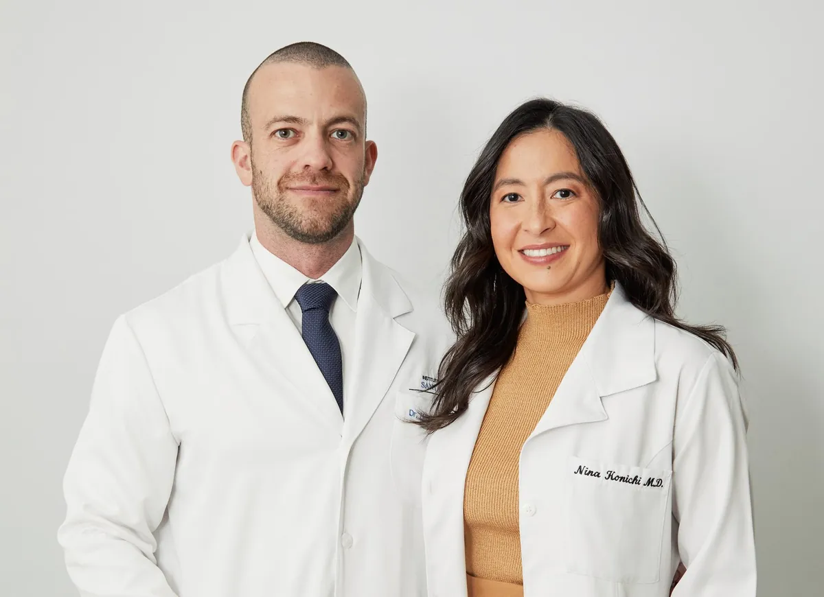 Dr. Henrique Leber e Dra. Nina Konichi, de jaleco branco, lado a lado.