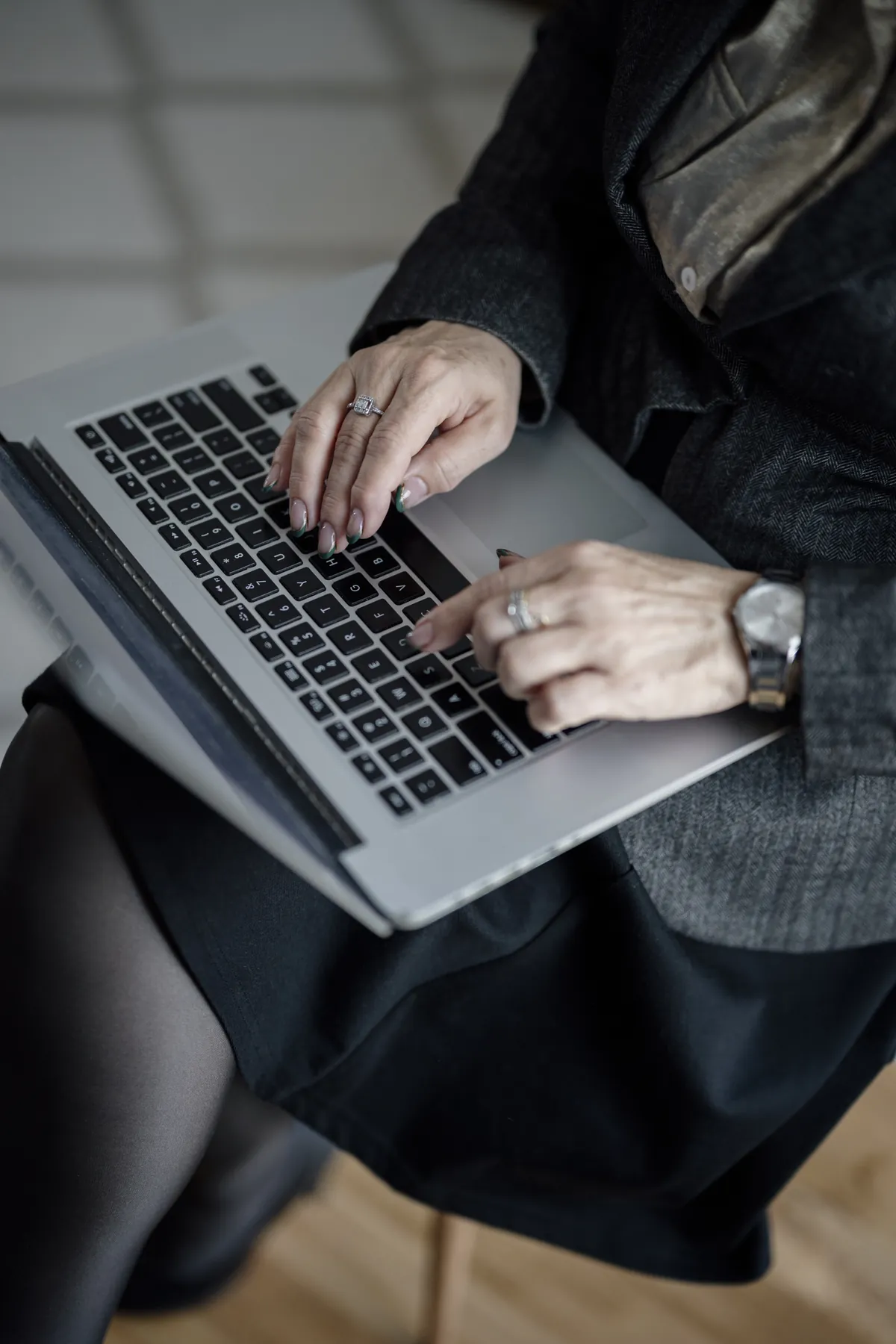 Mãos de uma adulta digitando em um laptop; rosto fora do enquadramento.