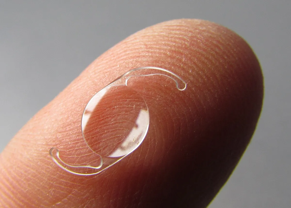 Lente intraocular transparente apoiada sobre a ponta de um dedo